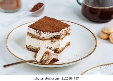 Tiramisu cake dessert served with coffee, biscuit and cocoa as ingredients on a bright white background. One piece
