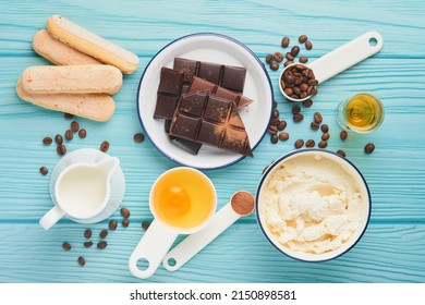 Tiramisu dessert. Ingredients for making dessert tiramisu. Cooking Italian food dessert Tiramisu with all necessary ingredients cocoa, coffee, mascarpone cheese on turquoise wooden background Top view