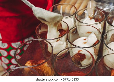 Tiramisu making. Woman hands holding a spoon and smeared cream on cookies