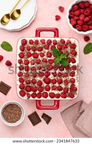 Tiramisu with raspberries and chocolate in a red ceramic form. Traditional Italian dessert. Top view