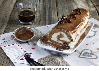 Tiramisu As Roulade Variant With Dark Chocolate Hearts And Coffee Glass On Table