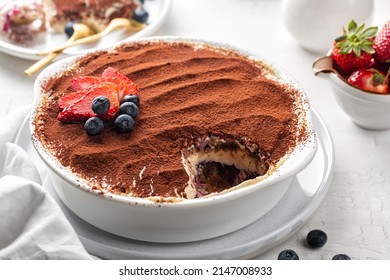 Tiramisu with strawberries and blueberries and berry layer, Italian dessert with ladyfinger biscuits, coffee and marscapone cheese in a casserole, powdered with cacao. Homemade.