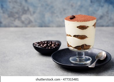 Tiramisu, traditional Italian dessert in glass on a grey stone background Copy space