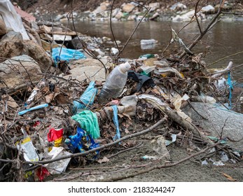TIRANA, ALBANIA, MARCH 2022: Flooded plastic rubbish at the river bank as waste management issue. River debris and plastic garbage mix on a sandy river shore. The need to raise environmental awareness - Shutterstock ID 2183244247