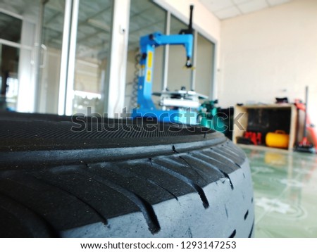 The tire on the floor has a tire changer on the background