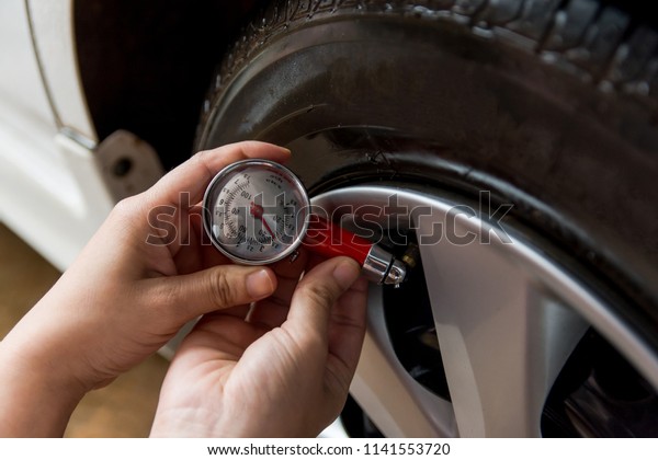 Tire pressure gauge : Hand\
holding pressure gauge checking air pressure for car tire. Safe\
driving.