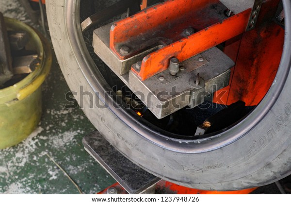Tire repairing,\
Motorcycle bike tires fixing with maintenance tools equipment\
orange color, Bangkok Thailand 10 November 2018, copy space on\
natural warm low light tone\
