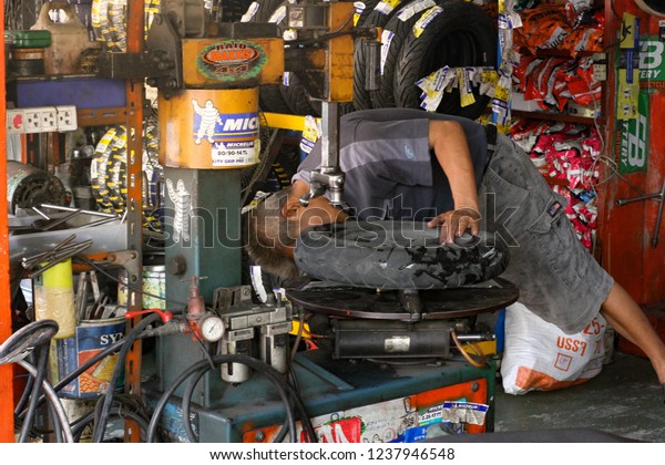 Tire repairing, Motorcycle tire pressure check\
with technician man hand close up Holding equipment\
tools,Transportation, Bangkok Thailand 18 November 2018, natural\
day low light tone with copy\
space.