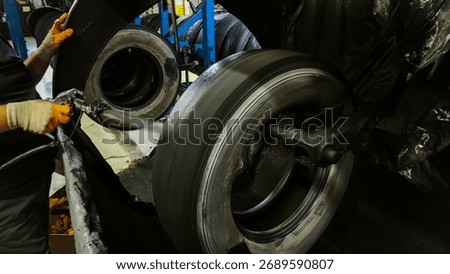 In the tire retreading workshop, cement solution is applied to the buffed surface before the tire retreading process.