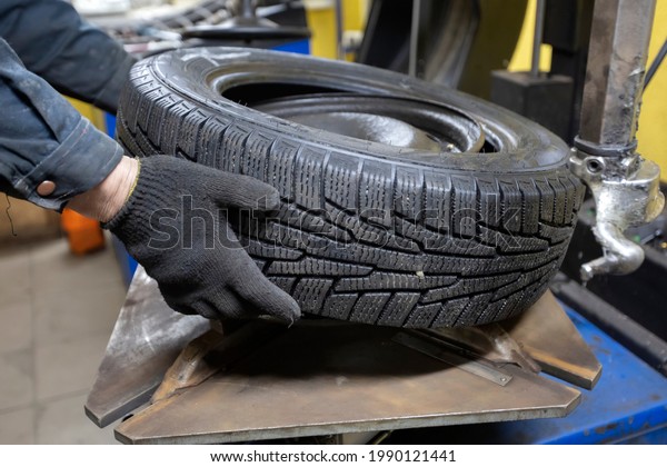 Tire service. The mechanic\'s hands hold the wheel\
of the car. Wheel repair.