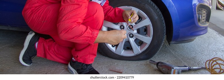 Tire Specialist In His Workshop While He Repairs A Punctured Wheel Of A Car With Patch And Putty. Do It Yourself Work. Horizontal Banner 
