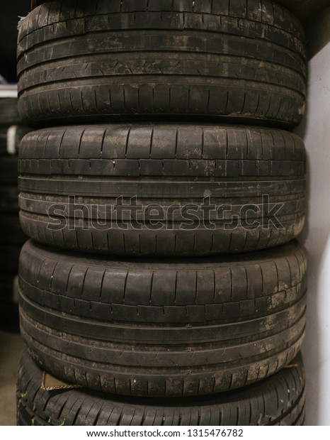 a tire stack with 3\
used summer tires, placed over each other, the tire profile\
visible, in a workshop