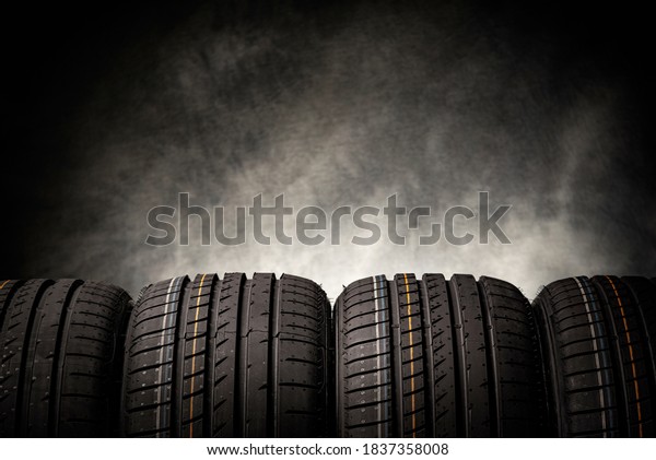 Tire stack background. Car tires on a black\
background. Four wheels.