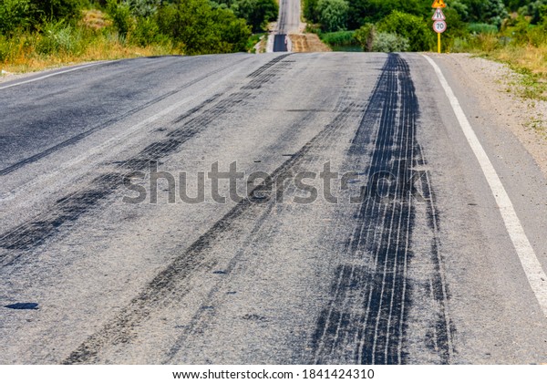Tire tracks on\
asphalt road. Brake traces