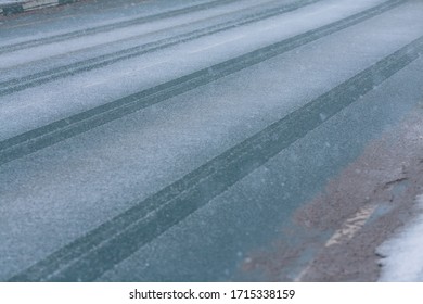 Tire Tracks On The Pavement, Wet Road. Bad Weather, Snowfall And Wet Snow Asphalt