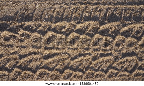 Tire tracks on the sand background.\
Traces from the tread of car on ground, Tire tread on wet ground as\
a result the grass dies.Car wheel marks on\
road.
