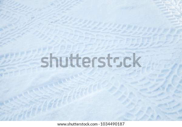 Tire tracks pattern on winter road covered with\
snow. Background texture
