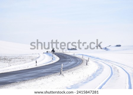 tire tracks in snow next to a cleared road