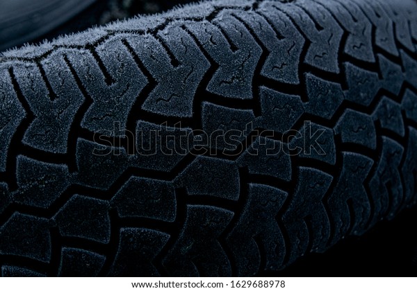 Tire tread close up covered in frost. Old tires\
dumped in a field. Industrial waste / rubbish background. UK rural\
crime.