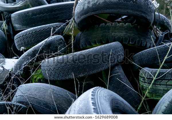 Tire tread close up covered in frost. Old tires\
dumped in a field. Industrial waste / rubbish background. UK rural\
crime.