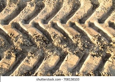 Tire Tread Footprints Of A Tractor On The Sand.