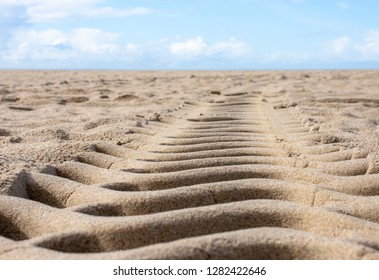 Tire Tread In Sand Low Angle To The Ground With Blue Sky Clouds Horizon