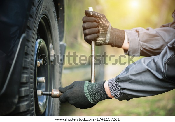 Tire worker\
removes wheel from a car close\
up.