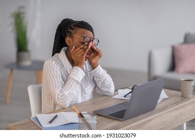 Tired african american business woman removing glasses and rubbing her eyes, working with laptop at home, copy space. Overworked black lady having tired eyes syndrome, living room interior - Shutterstock ID 1931023079