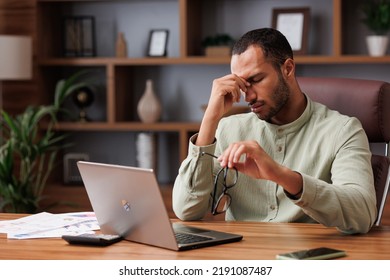 Tired african american businessman after exhausting paperwork taking off eyeglasses and feeling eye strain. Head ache, bad vision, chronic fatigue and eyestrain concept. Burnout and overwork concept - Shutterstock ID 2191087487