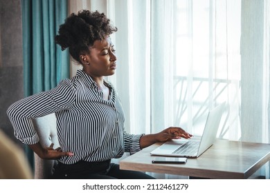 Tired African American Millennial Female Worker Sit At Desk Touch Back Suffer From Lower Spinal Spasm, Hurt Unhealthy Biracial Woman Stretch Have Strong Backache, Incorrect Posture Concept