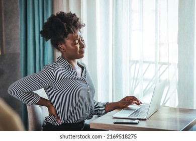 Tired African American Millennial Female Worker Sit At Desk Touch Back Suffer From Lower Spinal Spasm, Hurt Unhealthy Biracial Woman Stretch Have Strong Backache, Incorrect Posture Concept