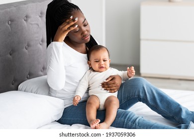 Tired African American Mom Sitting With Kid On Bed