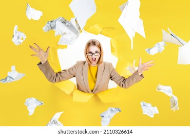 Tired angry female employee in stress. Deadline, information overload concept. Overworked blond young woman office worker is throwing documents, standing under paper rain. Big boss is furious.