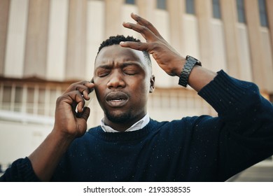 Tired, Angry And Stress Business Man Talking On An Annoying Phone Call Outdoors In A City. Frustrated, Pain Or Sick Black Male Entrepreneur With A Headache Or Migraine Outside A Urban Town