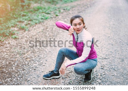 Tired Asain woman runner taking a rest after running hard on forrest mountain road, Young fitness girl running, exercise workout in nature road. Autumn city forest park in fitness Sports concept