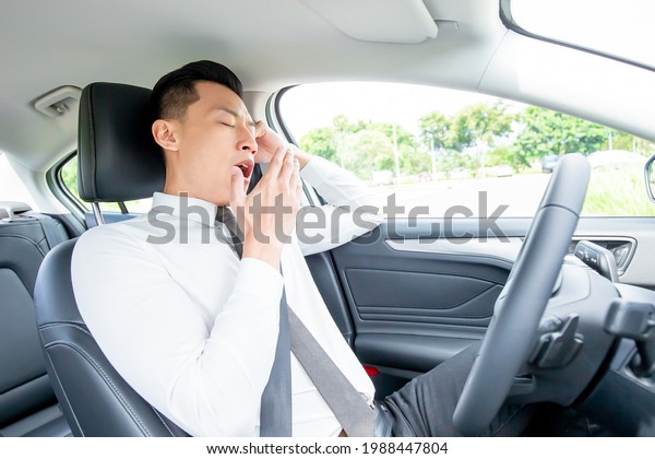tired asian businessman sleep and yawn in car\
while commutting