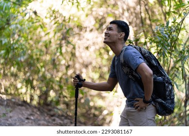 Tired and tired Asian male traveler with trekking gear and backpack resting. Take a break on your way from hiking, tourism concept. - Powered by Shutterstock