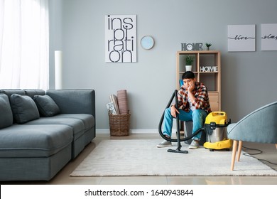 Tired Asian Man With Vacuum Cleaner At Home