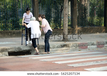 Tired asian senior woman with walker trying to climb the sidewalk after cross the road on crosswalk,facing the difficulties,barrier,tall footpath,different level floor, problems of disabled elderly