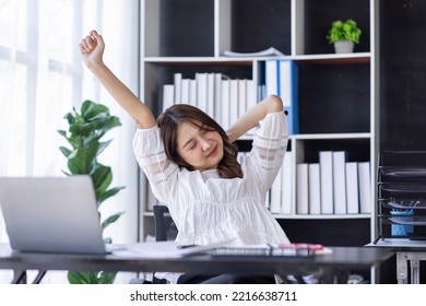 Tired Asian Woman Office Employee Staring At The Laptop Screen, Feels Boring And Melancholy. Bored Eastern Woman In Smart Casual Shirt Sits At The Desk