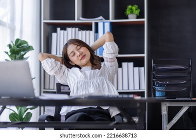 Tired Asian Woman Office Employee Staring At The Laptop Screen, Feels Boring And Melancholy. Bored Eastern Woman In Smart Casual Shirt Sits At The Desk