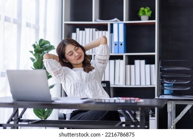 Tired Asian Woman Office Employee Staring At The Laptop Screen, Feels Boring And Melancholy. Bored Eastern Woman In Smart Casual Shirt Sits At The Desk