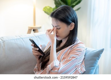 Tired Asian Woman Suffering Eyestrain Using Mobile Phone, Blue Light Is Harmful To Eyes.