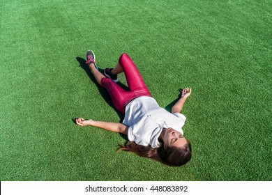 Tired Athlete Lying Down From Heat Exhaustion On Grass Park After Intense Workout. Exhausted Asian Runner Woman Taking A Break Sweating During Cardio Running Exercise Training In Summer Outdoors.