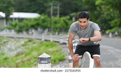 Tired Athletic Man Resting And Checking His Heart Rate Data On Smartwatch During Morning Workout