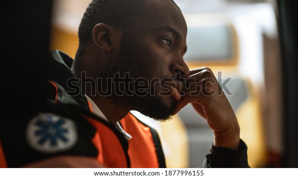 Tired Black\
African American Paramedic Tries to Rest in an Ambulance Vehicle\
Going for Emergency. Emergency Medical Technicians are on Their Way\
to a Call. Close-up Side View\
Shot.
