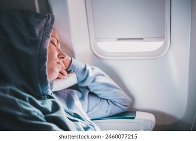 Tired blonde casual caucasian woman wearing sporty hoodie napping on seat while traveling by airplane. Commercial transportation by planes. Authentic image of real people - Powered by Shutterstock