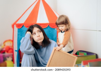 

Tired Bored Mom Having No More Energy In The Playroom. Exhausted Babysitter Feeling Fatigued While Active Child Plays Around Her

