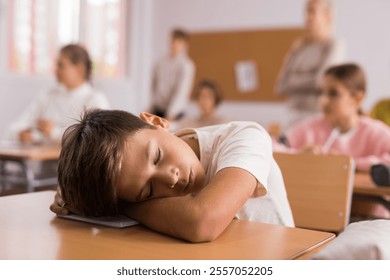 Tired bored teenage schoolboy sleeping at desk - Powered by Shutterstock