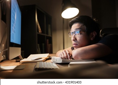 Tired Bored Young Man In Glasses Studying Using Books And Computer At Nighttime